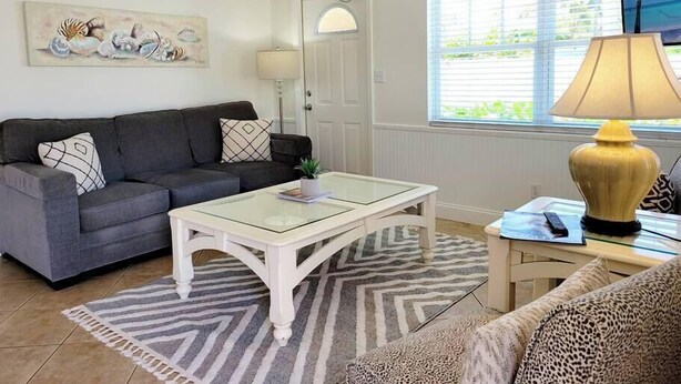 Un salon avec un canapé, une table basse, une lampe et un tableau au mur.