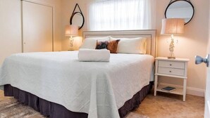 Quarto bem arrumado com cama, mesas de cabeceira e guarda-roupa.