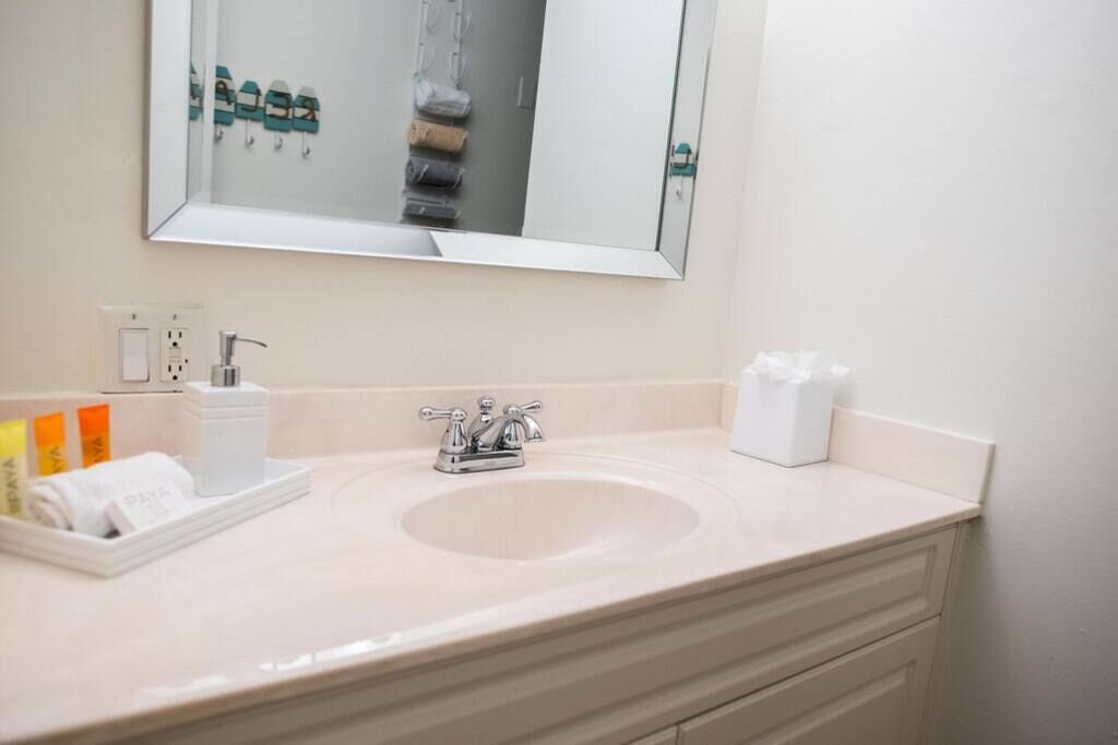 A bathroom with a sink, mirror, towel rack, and toiletries.