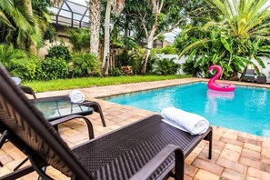 A pool area with lounge chairs and a flamingo float.