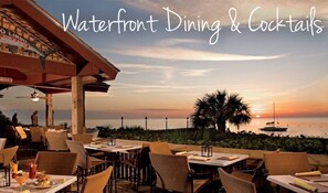 An outdoor dining area with tables and chairs, overlooking a sunset view.