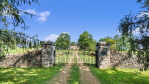 Une porte en pierre surmontée d’une grille métallique, qui mène à un bâtiment à la façade en briques.