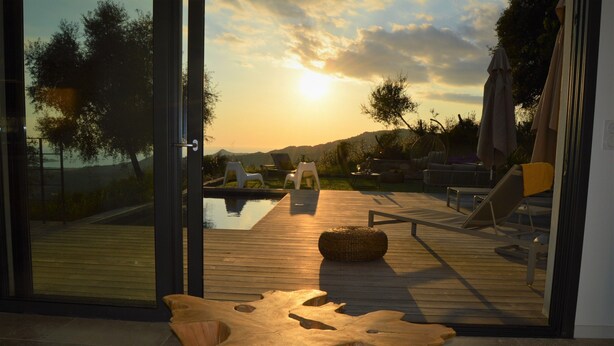 Una terraza moderna al aire libre con piscina, sillones de descanso y una mesa de madera.