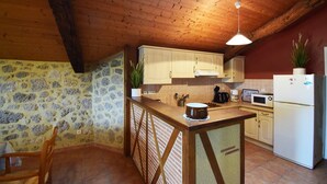 Eine rustikale Küche mit Steinwänden, Holzbalken und einer schrägen Decke.