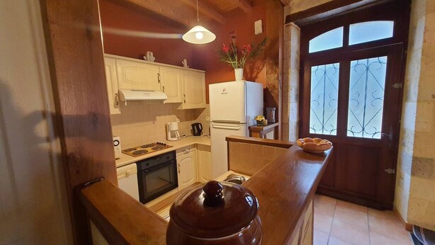 A compact kitchen with wooden cabinets, a stove, a refrigerator, and a large pot on the counter. - Gîte Nico Label Pêche - 4 pers proche du Gers (LANNES)