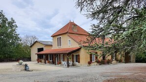 A two-story house with a red-tiled roof, a covered patio with outdoor seating, and a gravel driveway. - Gîte Nico Label Pêche - 4 pers proche du Gers (LANNES)