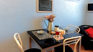 A dining area with a table set for two, a blackboard with 'Welcome' written on it, a vase with flowers, and a coffee pot. - Uno sguardo su Porta Palazzo (Turin)