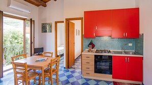 A kitchen with red cabinets, a blue and white checkered floor, and a dining area with wooden chairs and a table. - Casa Gallizza by Wonderful Italy (Cefalù)