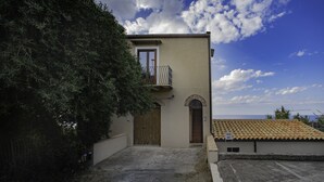 A building with a balcony, a door, and a small garden area. - Casa Gallizza by Wonderful Italy (Cefalù)