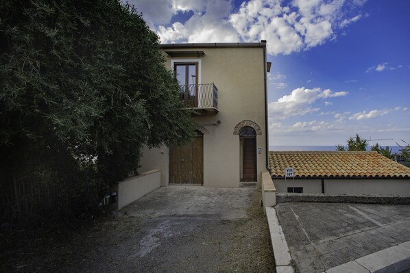 Un bâtiment doté d’un balcon, d’une porte et d’un petit jardin.
