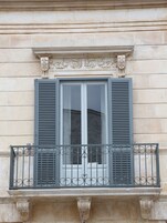 A building facade with a window featuring a balcony with ornate metal railings.