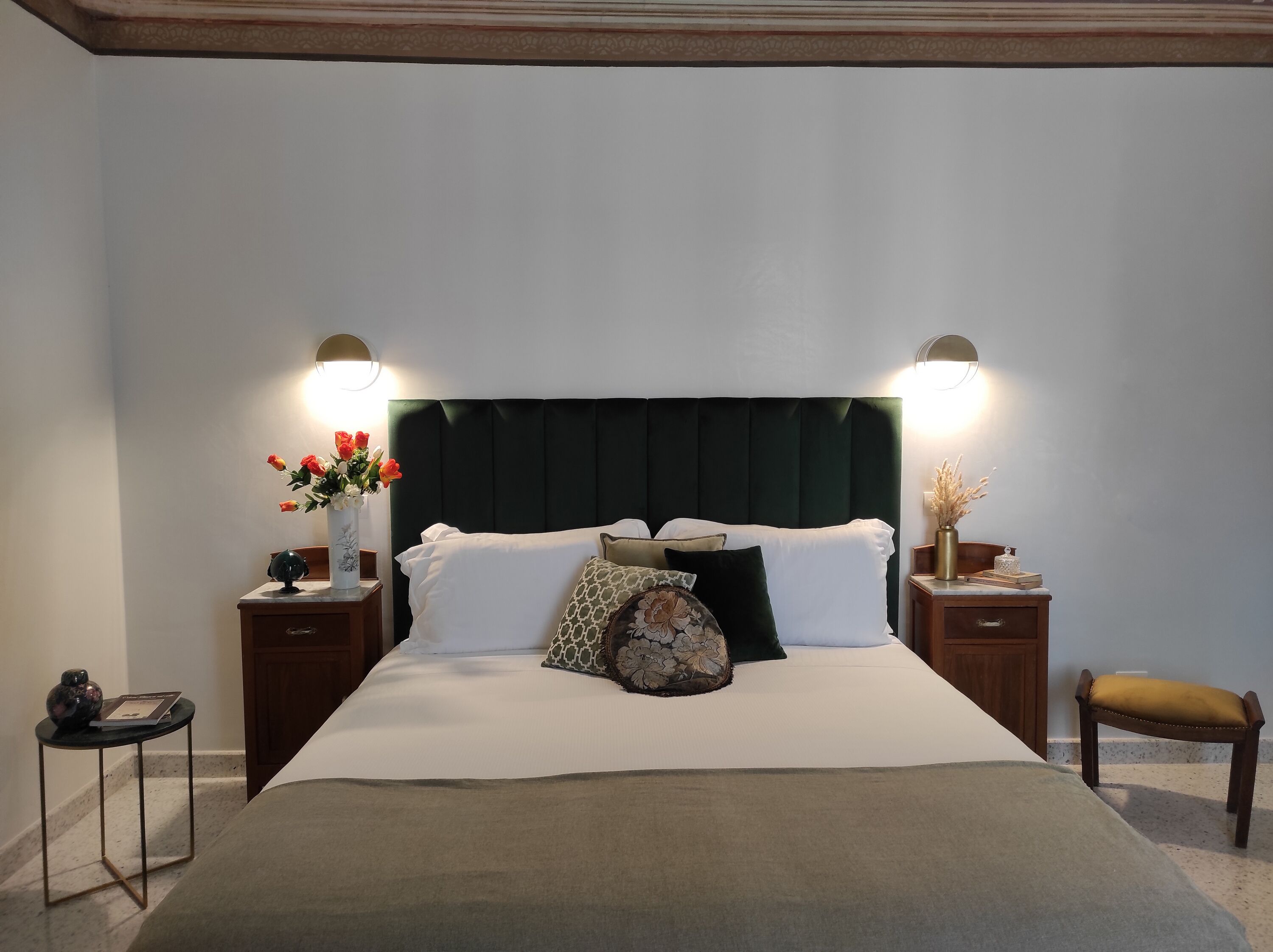 A neatly made bed with white linens, a dark headboard, and two bedside tables with lamps.