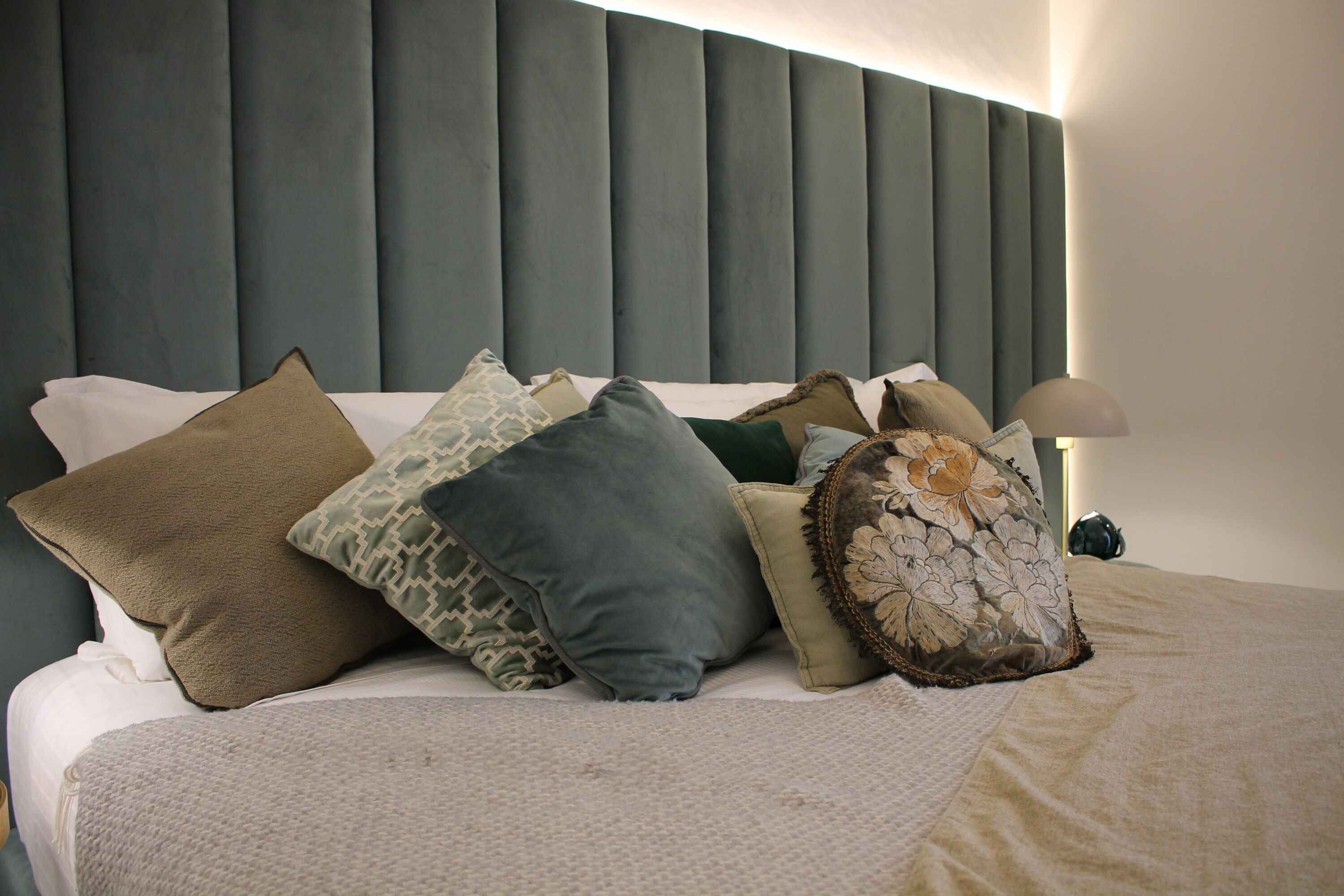 A neatly made bed with multiple pillows and a headboard.