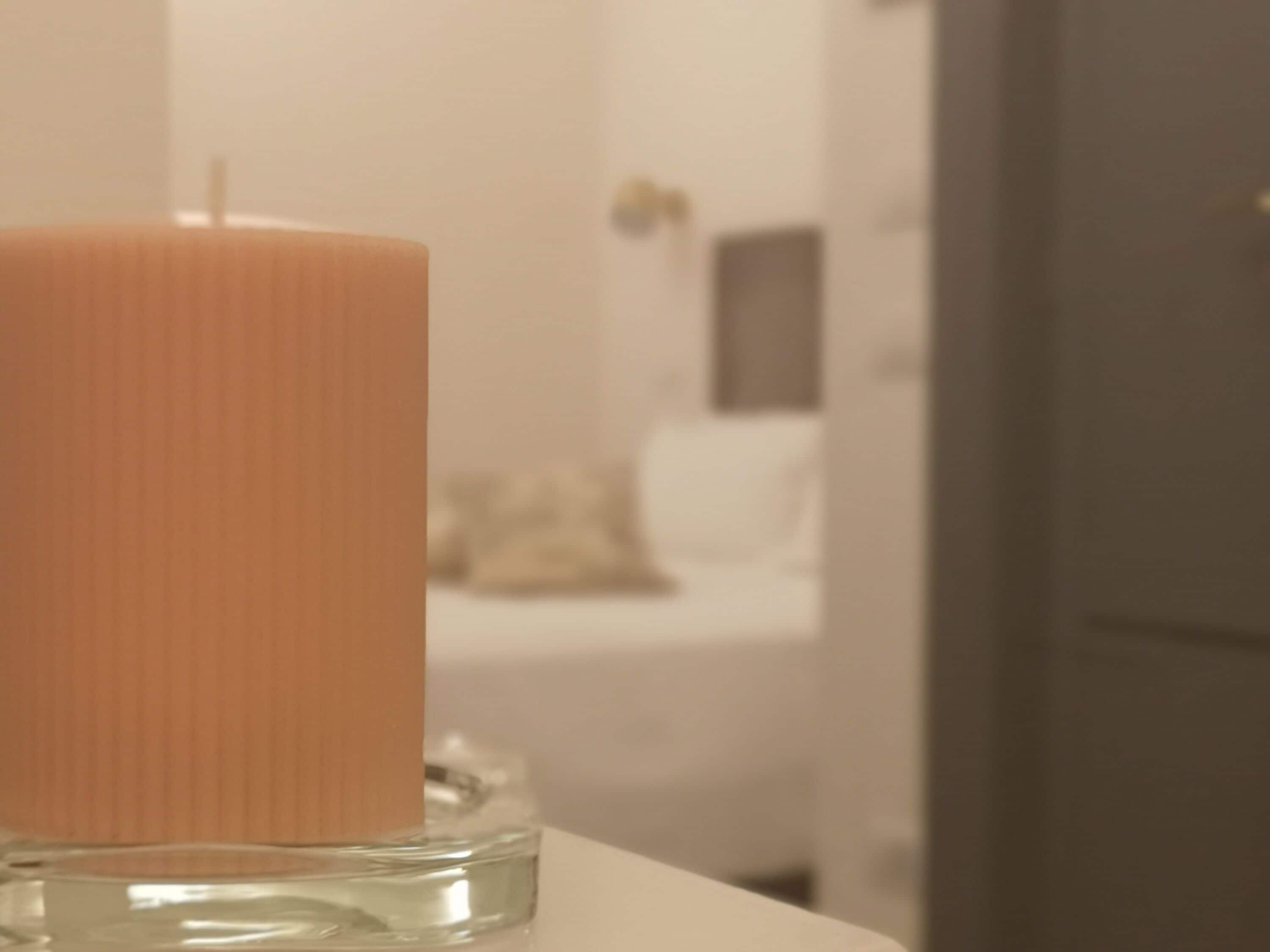 A candle in a clear glass holder on a white surface.