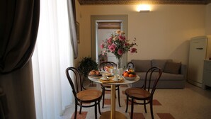A dining area with a round table, four wicker chairs, a vase of flowers, and a sofa in the background. - 1940 Luxury Accommodations by Wonderful Italy (Ostuni)
