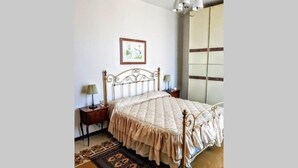 A bedroom with a bed, a nightstand, a lamp, a rug, and a wall-mounted picture. - Charme and Comfort near Cinque Terre by Wonderful Italy (La Spezia)