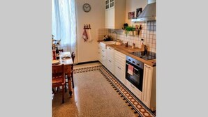 A kitchen with a wooden table, chairs, a clock on the wall, and a tiled backsplash. - Charme and Comfort near Cinque Terre by Wonderful Italy (La Spezia)
