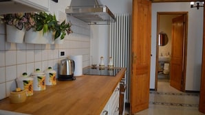 A kitchen with a wooden countertop, white tiles, a stainless steel range hood, and a view into the adjacent bathroom. - Charme and Comfort near Cinque Terre by Wonderful Italy (La Spezia)