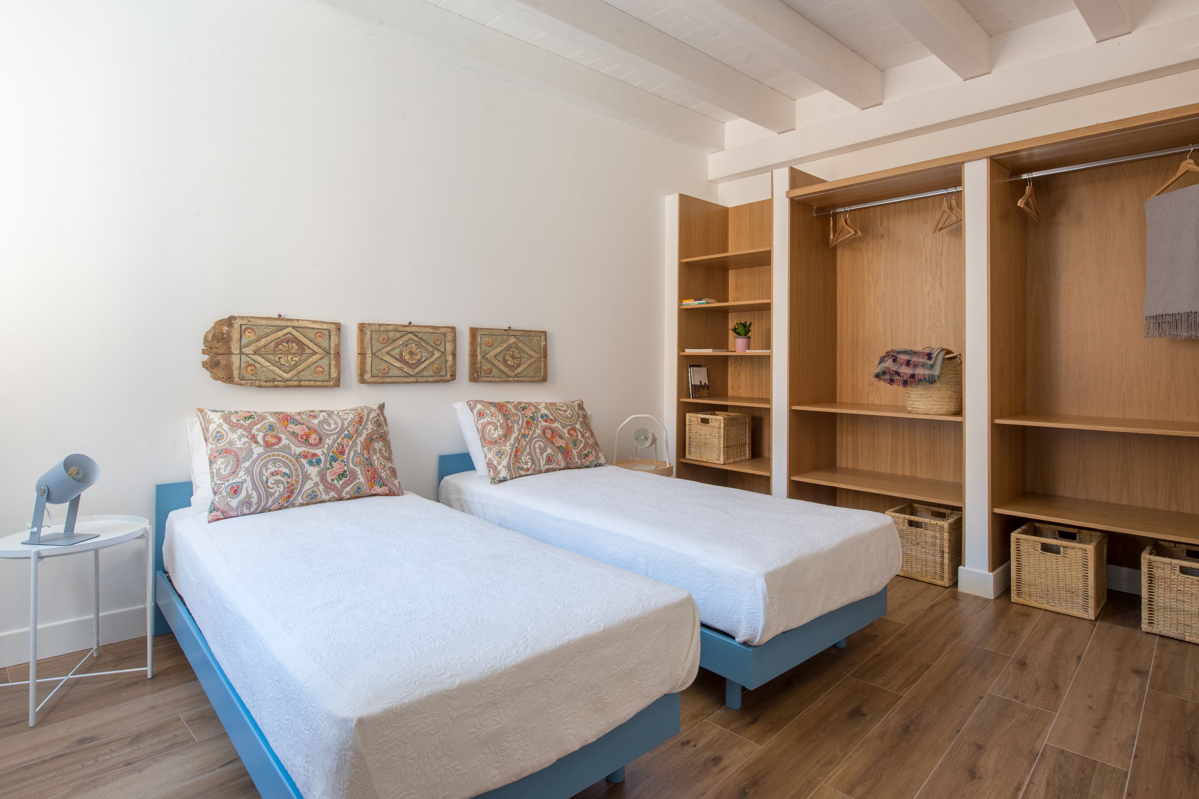 A bedroom with two beds, a wardrobe, and a small table.