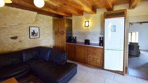 Una sala de estar acogedora con un sofá de cuero negro, armarios de madera y una pared de piedra.