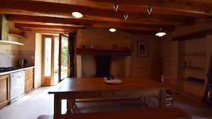 Una cocina rústica con vigas de madera, una mesa grande y una chimenea.