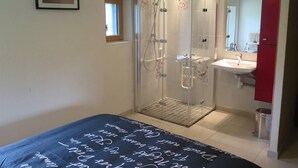 Un baño moderno con ducha de vidrio, lavamanos y espejo.
