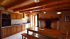 Una cocina con armarios de madera, estufa, microondas y un banco de madera.