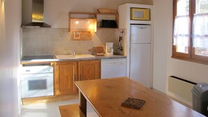 A compact kitchen with wooden cabinets, a built-in oven, a sink, and a refrigerator.