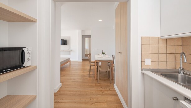 Una cocina moderna con estantes de madera, microondas integrado y un lavabo.