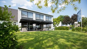 Un hôtel moderne doté d’un espace extérieur couvert avec des sièges, d’une pelouse bien entretenue et d’un terrain de jeux.