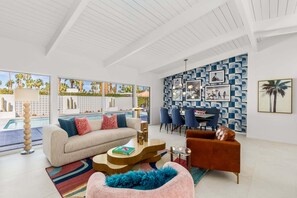 Uma sala de estar moderna com vista para a piscina, uma área de jantar e uma parede com padrão.