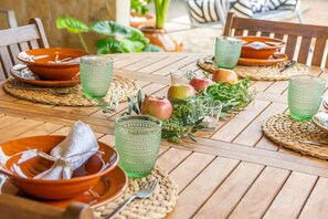 Ein Holztisch, gedeckt mit grünem Glas, orangefarbenen Tellern und frischem Obst.