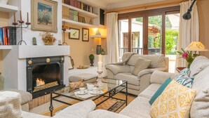 A cozy living room with a fireplace, comfortable seating, bookshelves, and a view of the outdoors. - CA NA ROSA (DE SELVA) - Apartment with private pool and garden near the mountains. Free Wi (Selva)