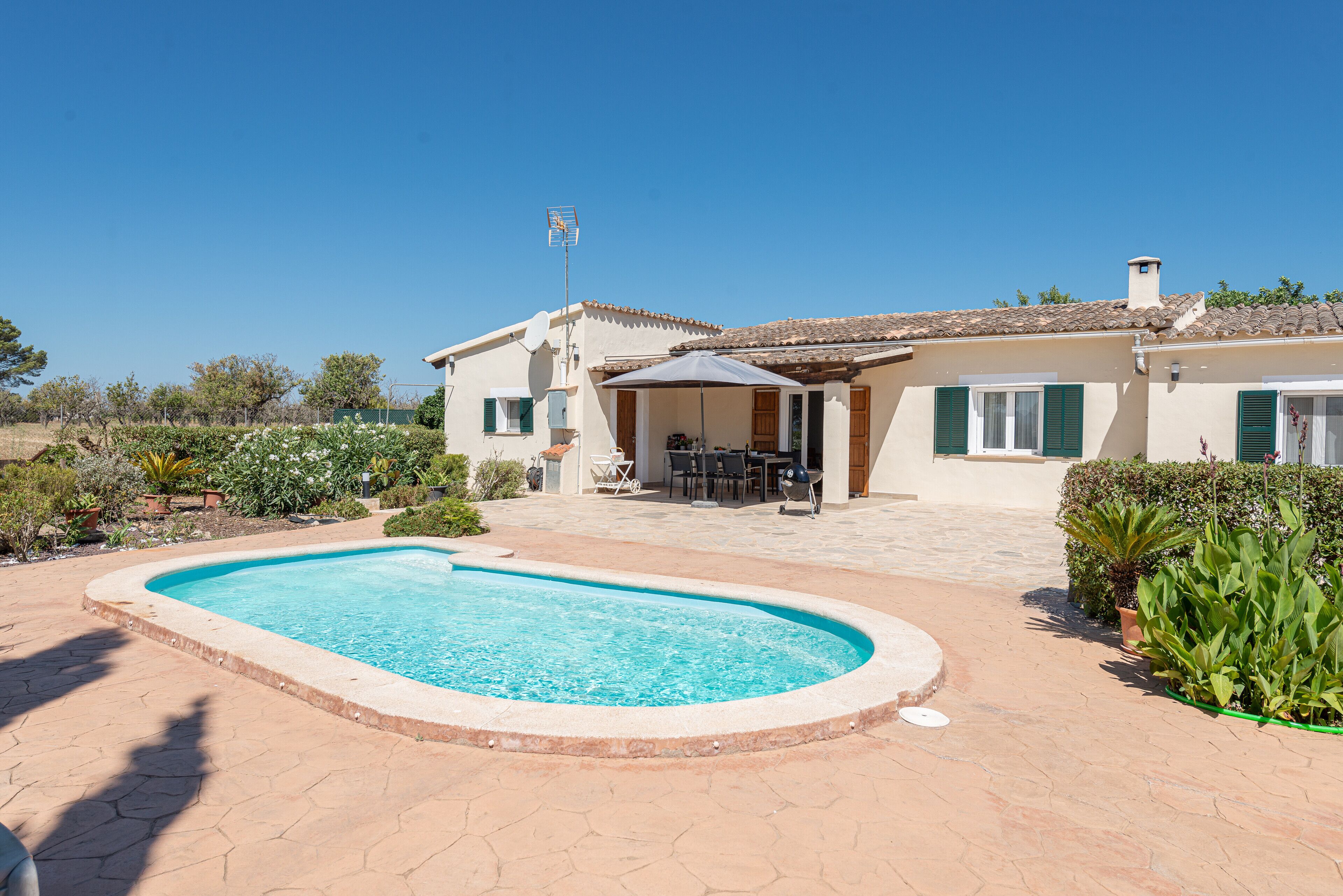 Une maison avec une piscine, du mobilier de jardin et un jardin.