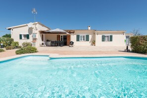 Une maison avec une piscine, du mobilier d’extérieur et une antenne parabolique.
