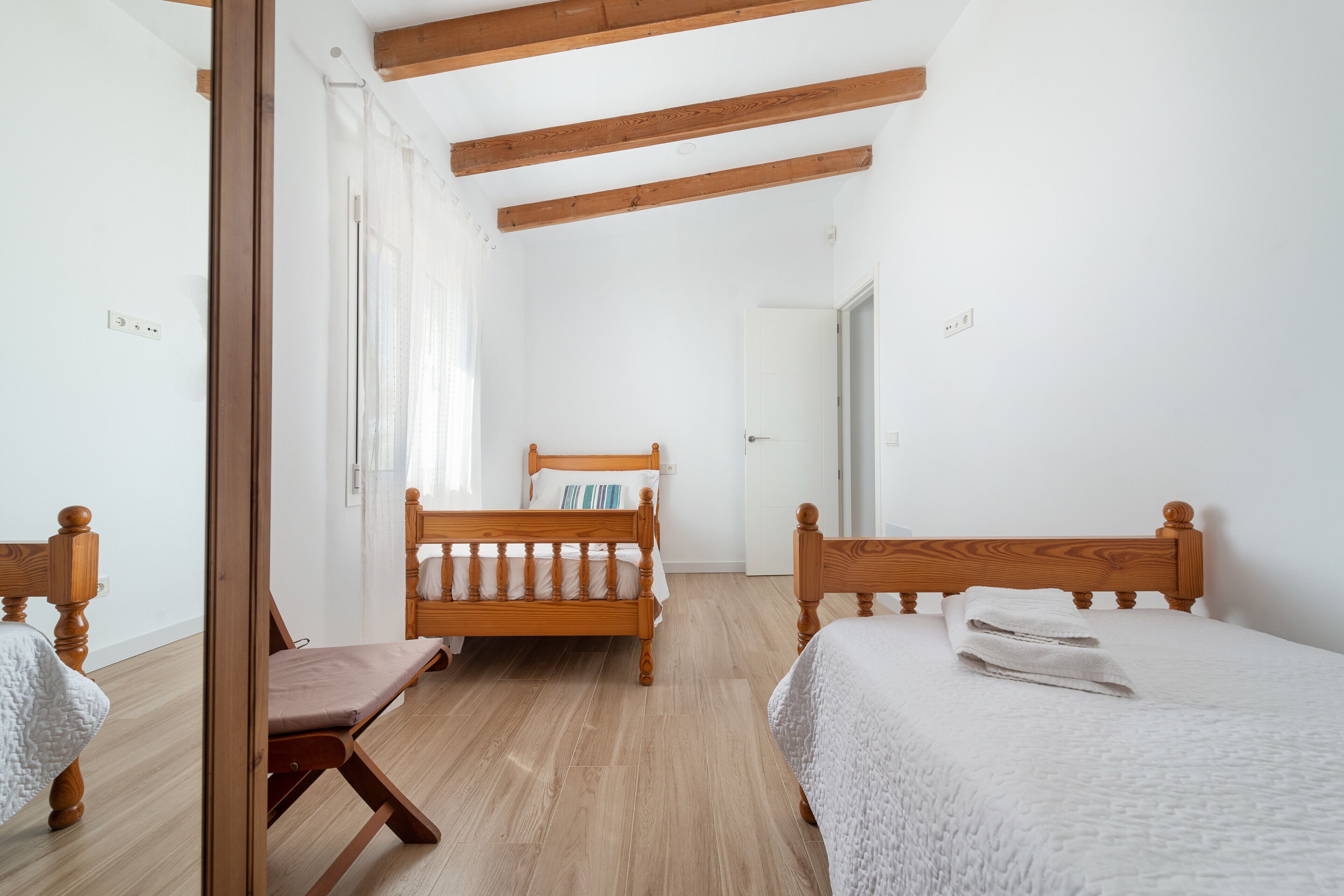 Ein Schlafzimmer mit einem hölzernen Bett, einem Holzstuhl und Holzboden.