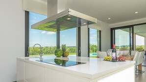 Una cocina moderna con una isla grande, estufa integrada y vistas a una piscina.