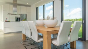 Una cocina moderna con armarios blancos, una campana de acero inoxidable y un ventanal con vistas a un paisaje verde.