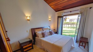 Ein Schlafzimmer mit einem großen Bett, zwei Wandleuchten, einem Nachttisch und einem Fenster mit Vorhängen.