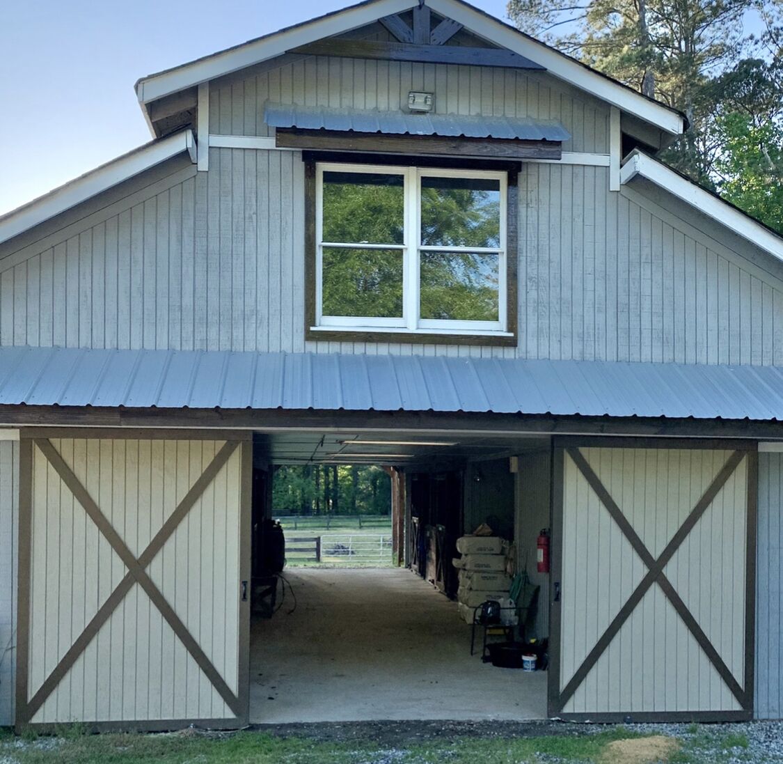 A barn-style building with a large window and open garage doors.