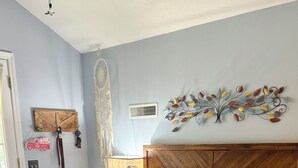 A bedroom with a bed, a bedside table, a wall-mounted dreamcatcher, and a wall decoration. - Regal Ranch Retreat *DOG & HORSE FRIENDLY* (Oxford)