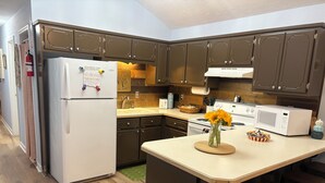 A kitchen with dark brown cabinets, a white refrigerator, a microwave, and a wooden island with stools. - Regal Ranch Retreat *DOG & HORSE FRIENDLY* (Oxford)