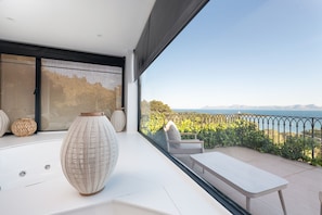 A balcony with a view of the sea, a table, and two chairs.