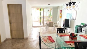Un comedor amplio con una mesa de vidrio, sillas y una lámpara de techo.