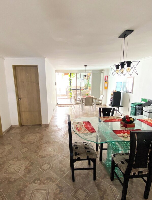 Un comedor amplio con una mesa de vidrio, sillas y una lámpara de techo.