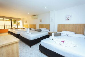 A hotel room with three beds, a wooden desk, and a view of the outdoors. - HOTEL COLORES BOUTIQUE    (Medellín)