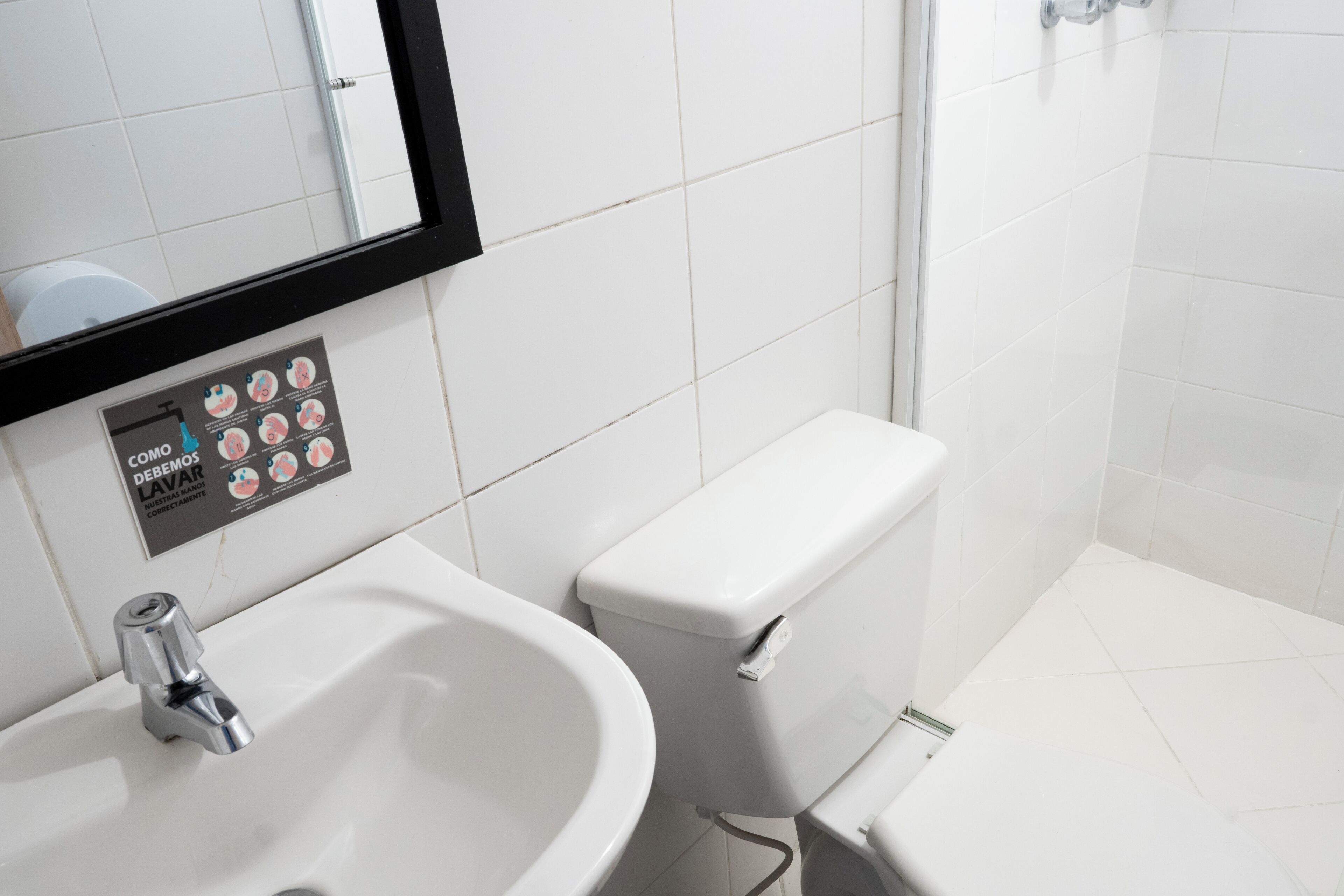 A bathroom with a white sink, a toilet, and a mirror.