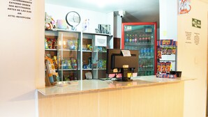 Zona de recepción con un monitor de computadora, un reloj y un refrigerador lleno de bebidas.