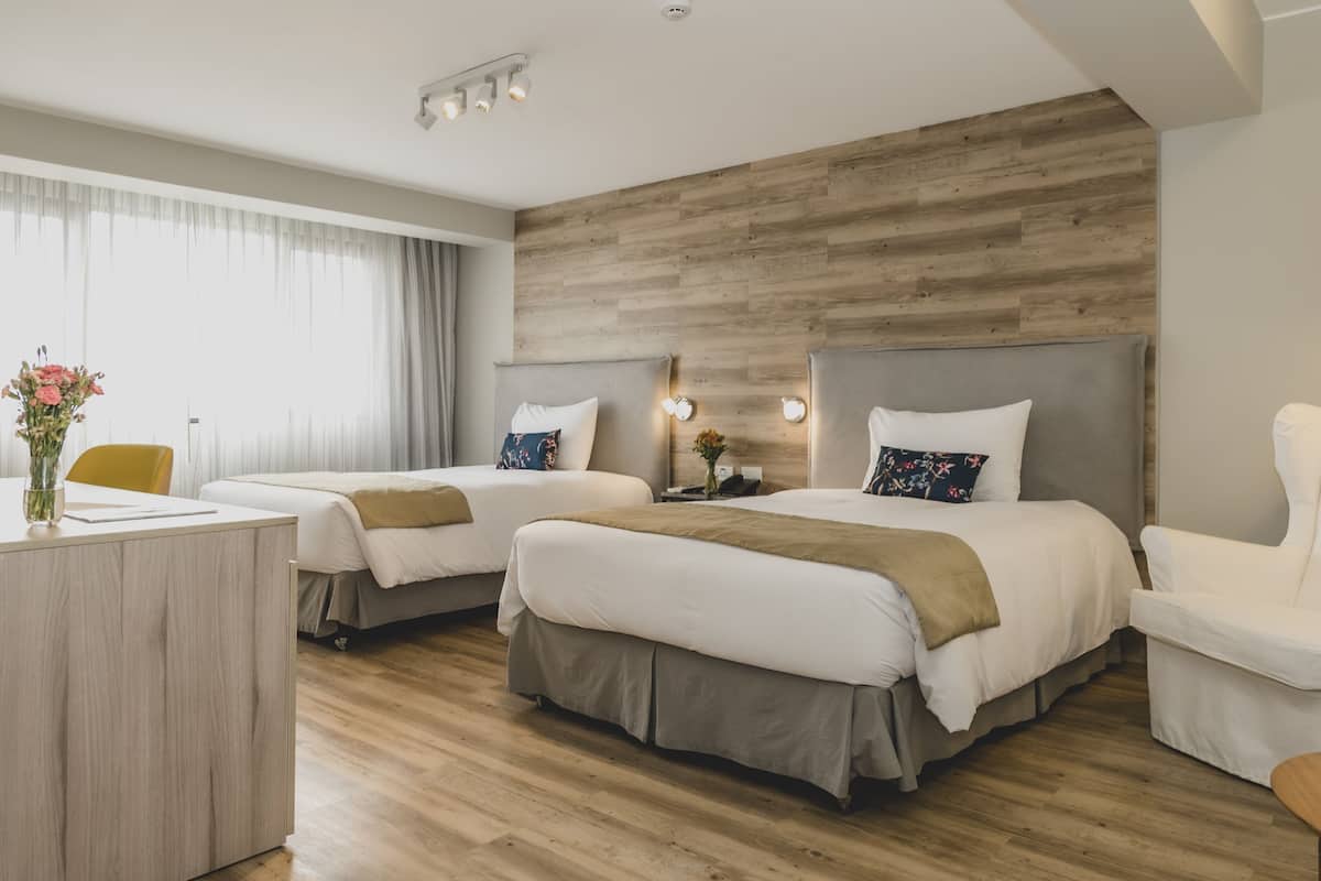 Habitación de hotel con dos camas, un escritorio y una silla.