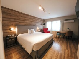 Un dormitorio con una cama grande, un escritorio, una silla roja y una pared de madera.